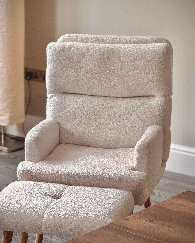 Sillón tapizado en tonos crema junto a una ventana, en un espacio tranquilo